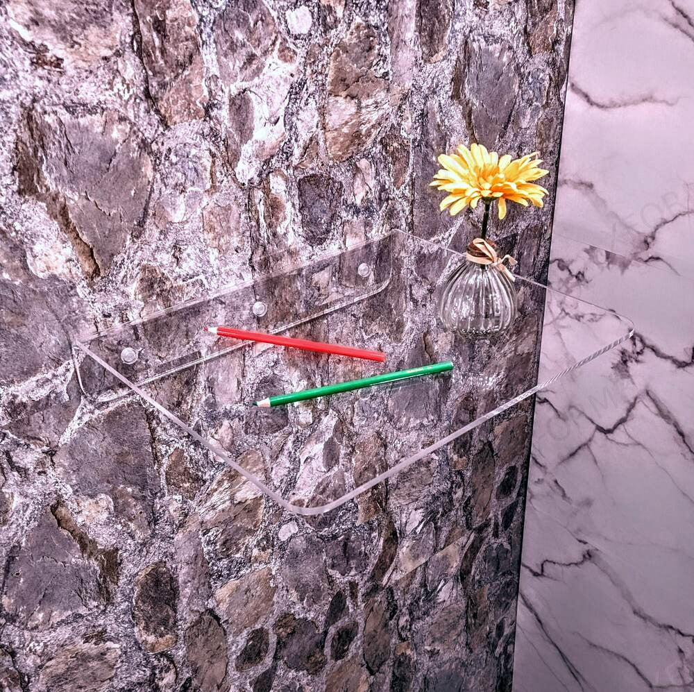 Clear shelf holding a small flower against a textured wall